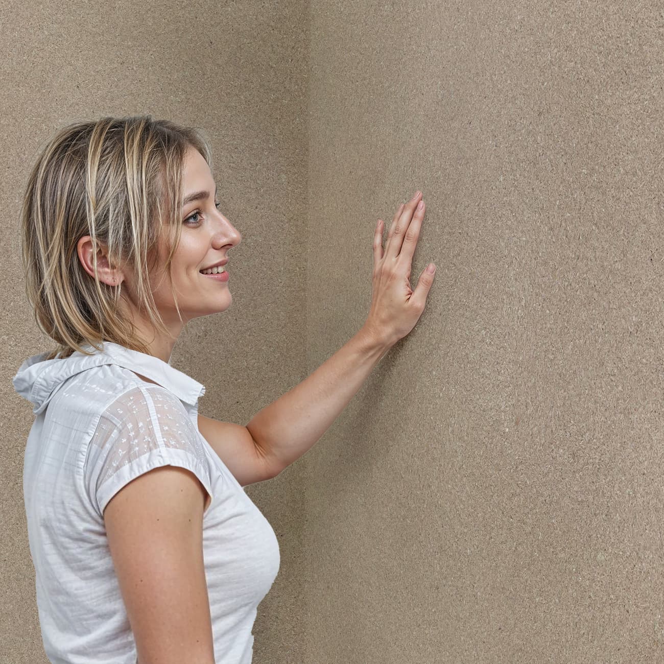 Mână feminină atingând textura tapetului Belka taupe autoadeziv